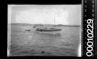 Raised decked motor launch towing a small rowboat, Sydney Harbour