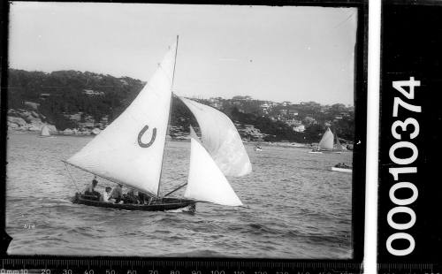 16-foot skiff on Sydney Harbour featuring a horseshoe emblem on the mainsail