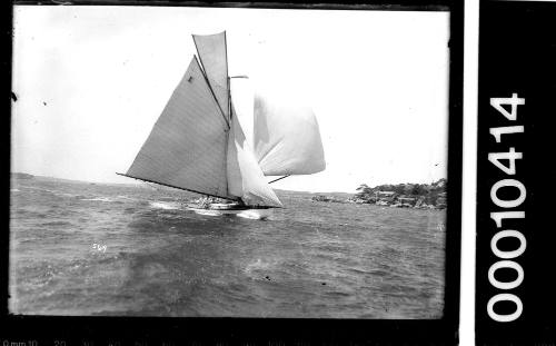 Sailing vessel with the number '2' on the mainsail sailing near rocky shoreline, Sydney Harbour