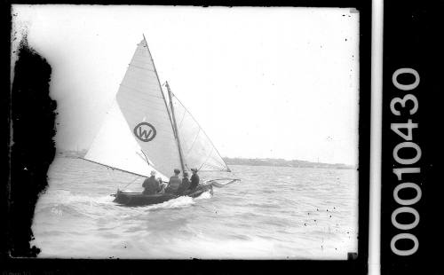 16-foot skiff on Sydney Harbour displaying an emblem of the letter 'W'