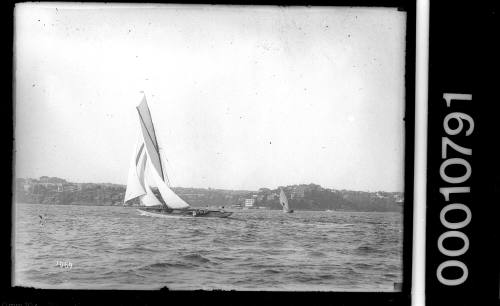 Yacht under sail on Sydney Harbour with 18-footer CUTTY SARK in the distance
