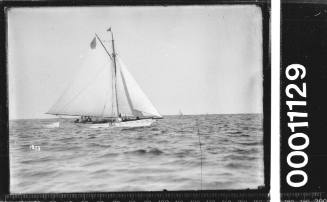 yacht towing dinghy offshore, likely near Sydney Heads