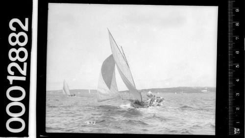 Stern view of a single masted yacht under sail on Sydney Harbour