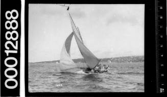 Stern view of a yacht under sail with crew in the cockpit and seated on the bulwark, Sydney Harbour