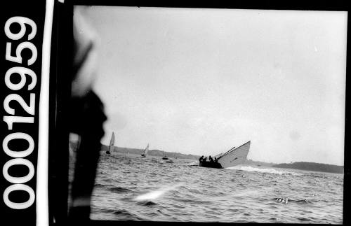 Single masted yacht with exclamation mark on the mainsail about to capsize in Sydney Harbour