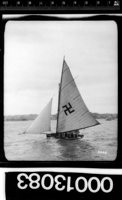 Yacht under sail on Sydney Harbour with a swastika emblem on the mainsail