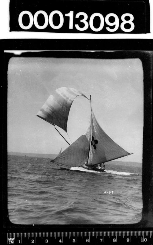 Yacht displaying an emblem of a dark cross with a light centre on the mainsail, Sydney Harbour