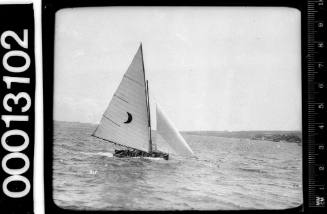 Yacht under sail on Sydney Harbour with a crescent moon emblem on the mainsail