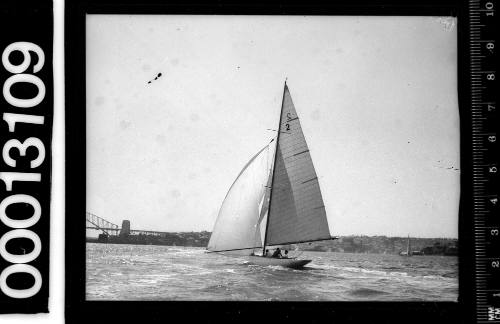 Sailing vessel with the number '2' on the mainsail underway near the Sydney Harbour Bridge