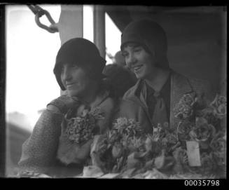 Two women passengers on board TSS ORUNGAL, one is holding a bouquet of flowers