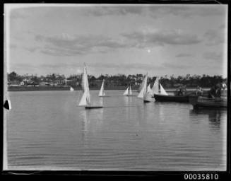 View of model sailing ships in harbour near shoreline.