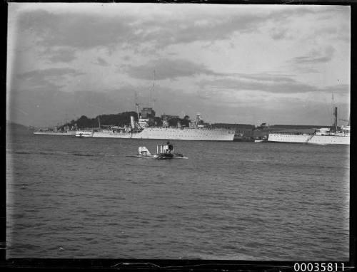 View of 3 warships and seaplane in harbour.