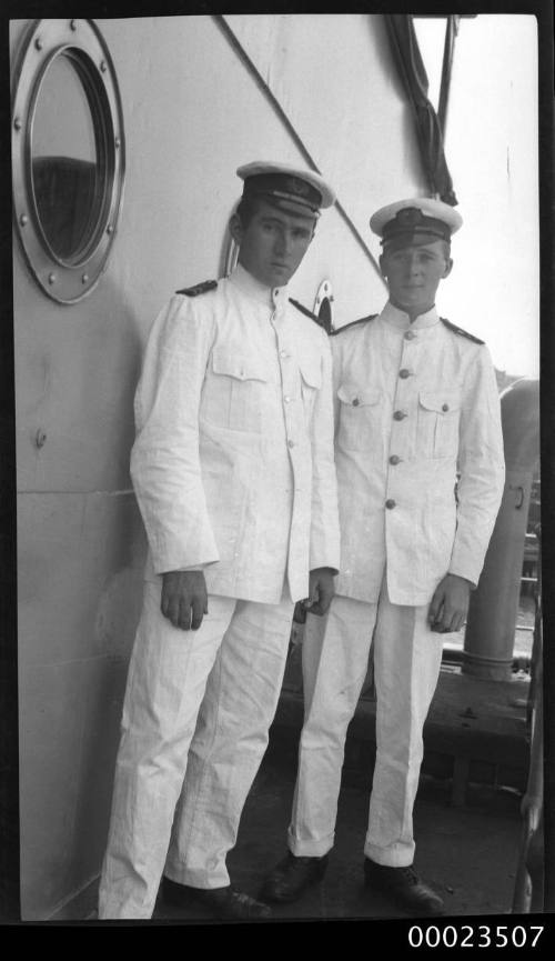 Portrait of two merchant officers standing next to a porthole on a ship