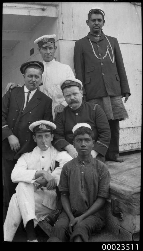 Group of six men, two wearing merchant marine uniforms, two wearing naval jackets and two in Indian style clothing