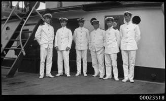 Six men in white naval officer uniforms standing on deck