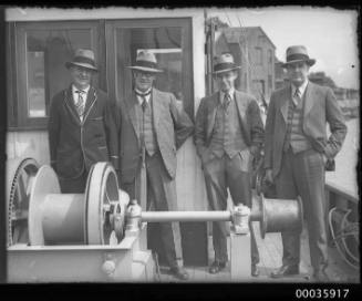 Four men wearing suits on deck of COAST GUARD.