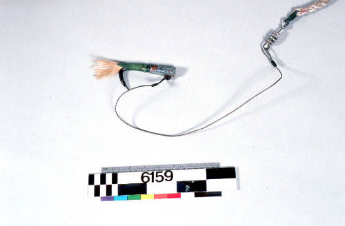 TUNA FISHING LURE, ATTACHED TO POLE (OOOO6158), METAL HOOK, WHITE FEATHERS ATTACHED TO SHAFT BY A SECTION OF GREEN TRANSPARENT PLASTIC HOSE, LENGTH OF METAL ROPE ATTACHED TO HOOK