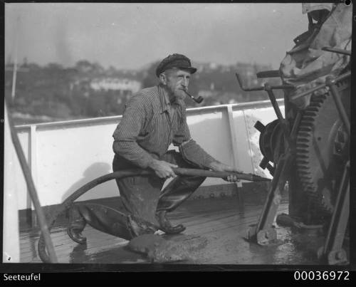 Boatswain Karl Muller smoking a pipe and hosing the deck of SEETEUFEL