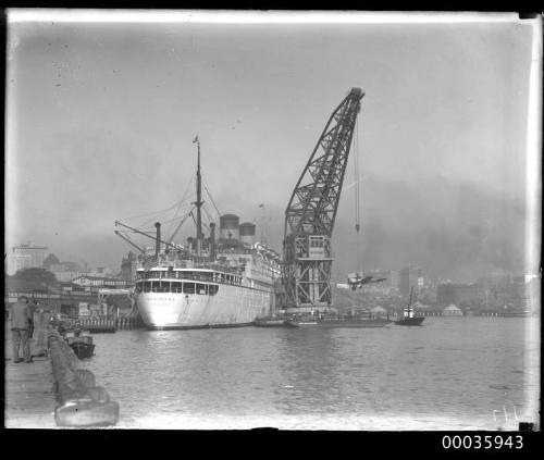 Floating crane unloading a fighter plane from the MARIPOSA during WWII