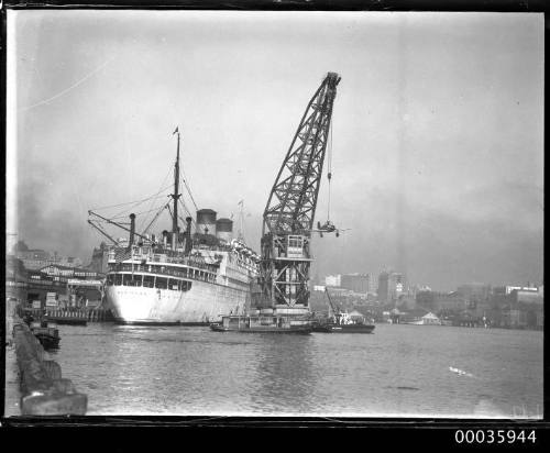 Floating crane unloading a fighter plane from the MARIPOSA during WWII