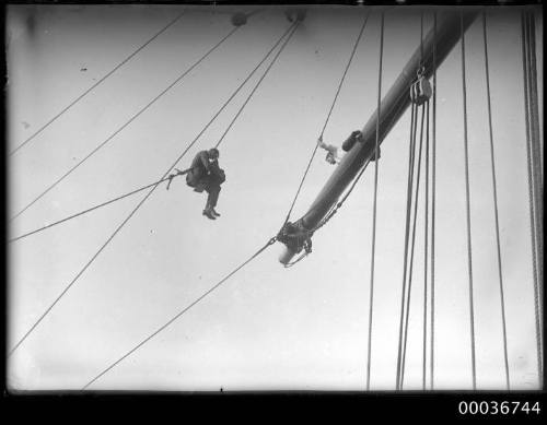 A photographer and crew member on upper rigging.