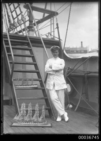 Image of an apprentice with two ship's models on deck of ELGINSHIRE.