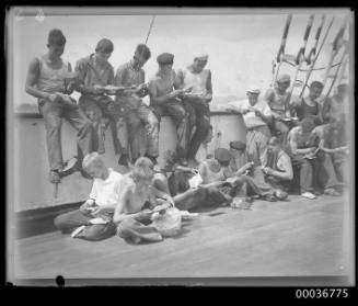 On deck of MAGDELINE VINNEN showing crew members reading mail.