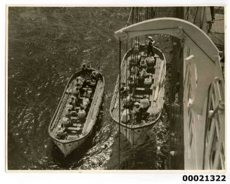 Two lifeboats being lowered down the side of an unidentified ship