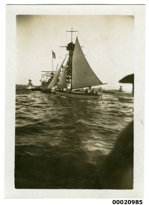 Sailing boat with United States Navy battleship behind in Sydney Harbour