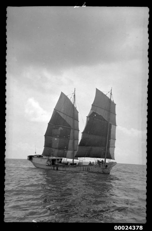 Large two masted vessel under sail with crew on deck