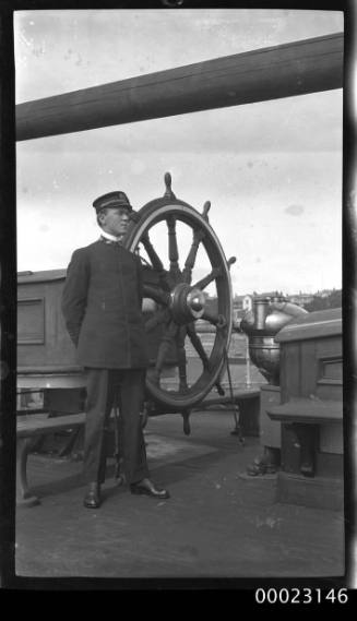 First Officer Ray Milton Sterling standing next to the ship's wheel of E R STERLING