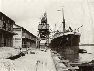 View of the docked ship COCHRANE alongside a moving crane in a west African port