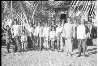 View of a crowd in front of a thatched hut  