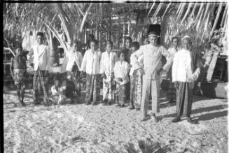 View of a crowd in front of a thatched hut 