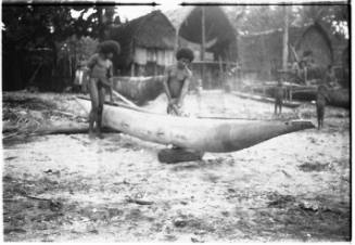 View of two men hollowing a dugout canoe