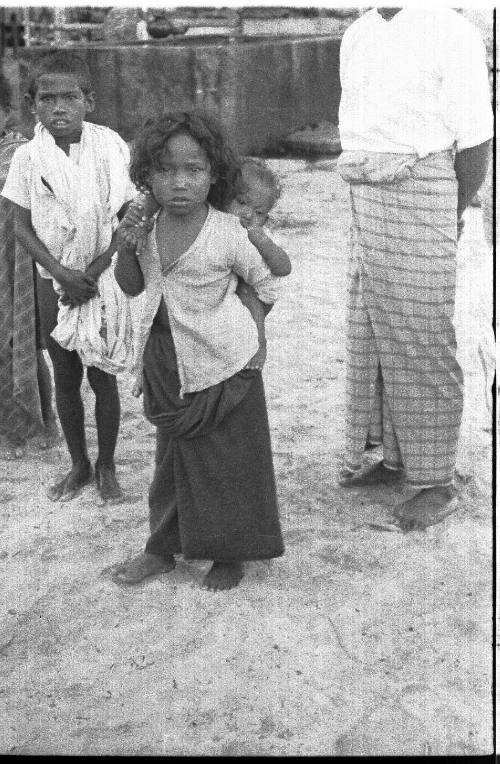 View of young girl carrying a baby on her back