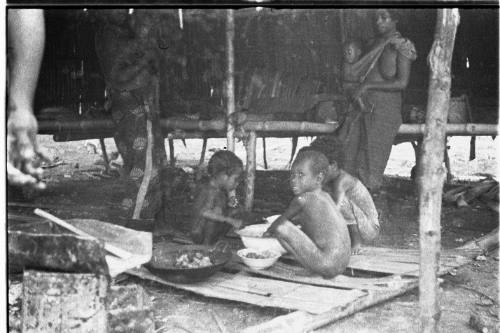 View of women and children inside a hut