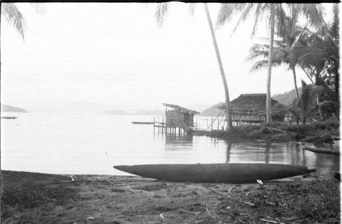 View of a canoe and huts along the water's edge