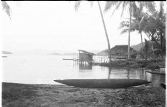 View of a canoe and huts along the water's edge