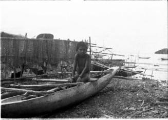 View of a child sitting in a dugout canoe