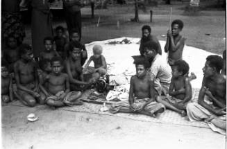 View of a group of people seated on a woven mat