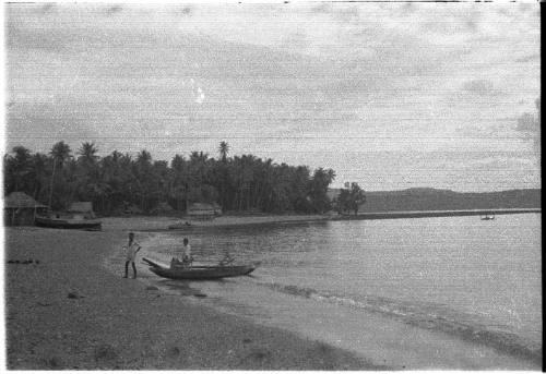 View of two men and a canoe at the water's edge