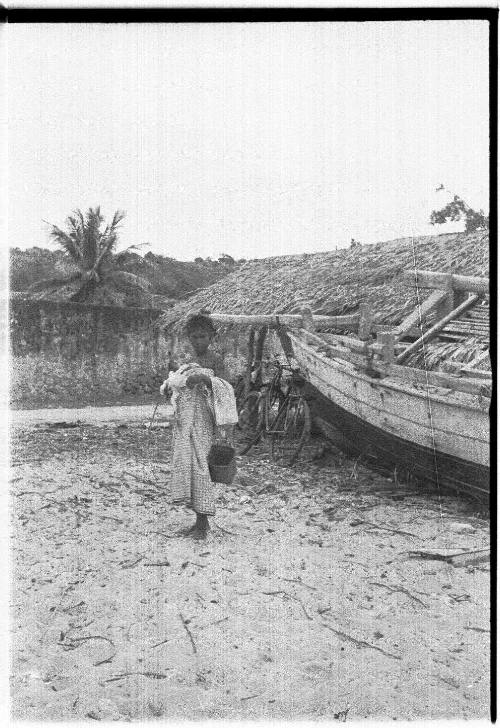 View of a girl beside a canoe on a beach