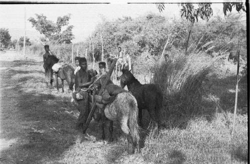 View of a group of men and horses on a grassland