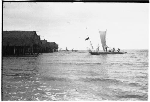 View of a canoe approaching a coastal village on stilts 