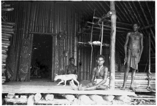 View of residents and a dog on a hut's verandah