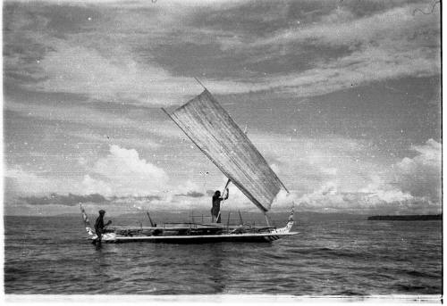 View of an outrigger canoe with sail hoisted 