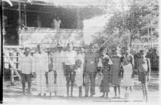 View of people lined up in front of a stilted hut 