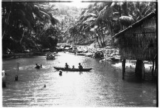 View of children playing in canoe and swimming in river 