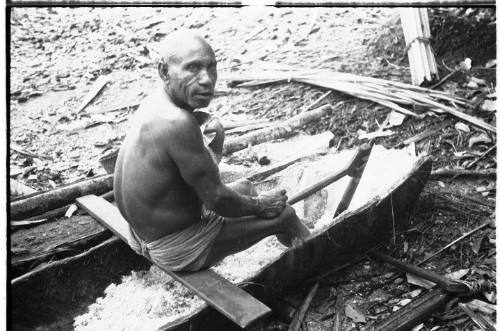 View of a man working the inside of a canoe